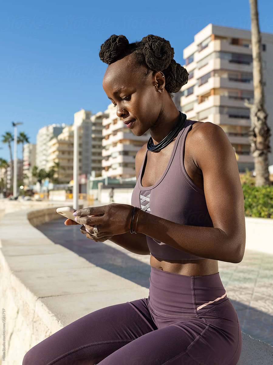 Black sportswoman using smartphone on border