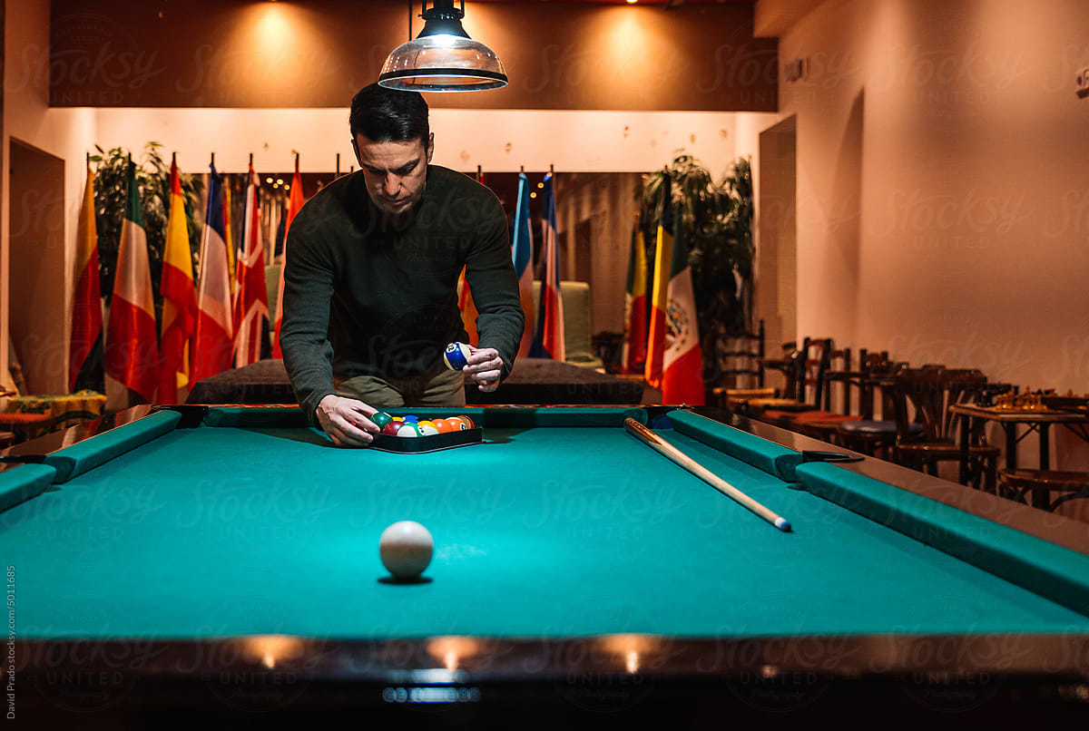 Focused man placing balls in rack before playing pool