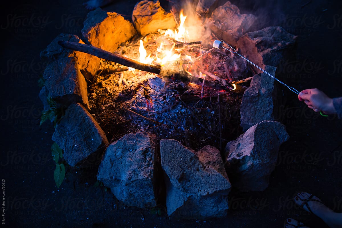 roasting a marshmallow over a campfire at night
