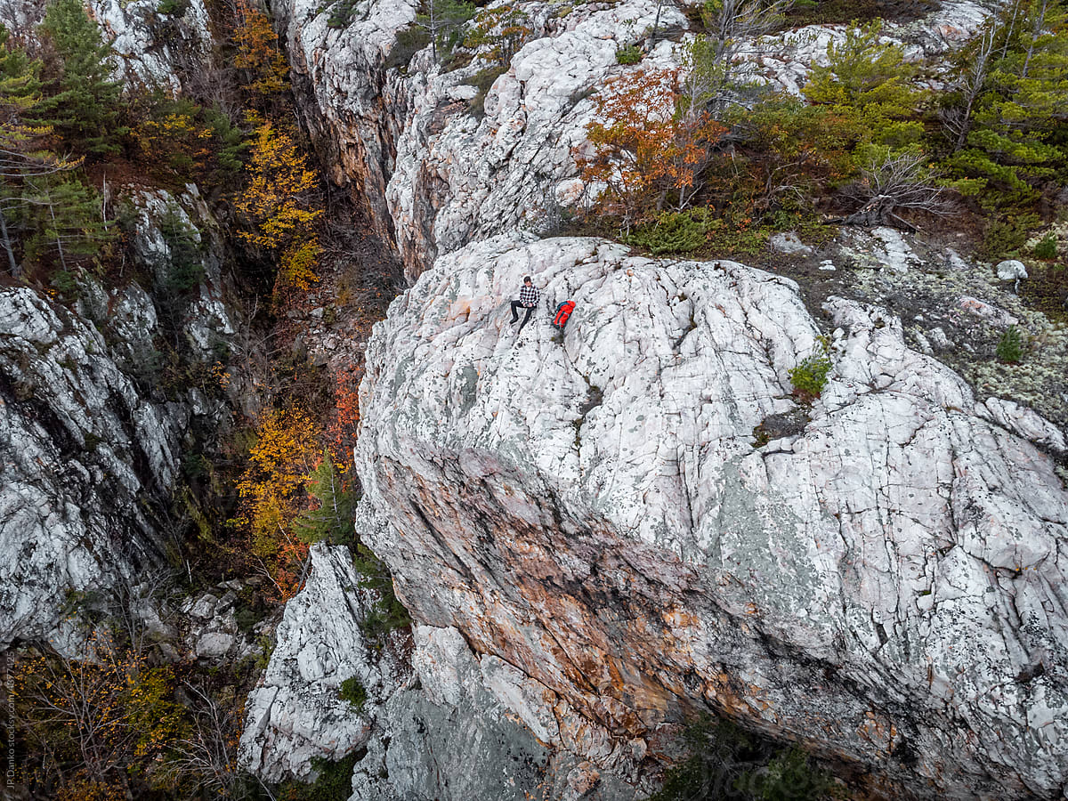 Man Sitting on Edge of Rocky Mountain Cliff in Autumn
