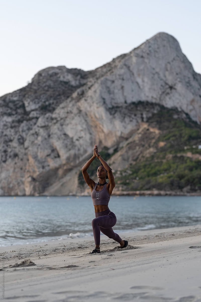 Black woman doing Warrior pose near cliff