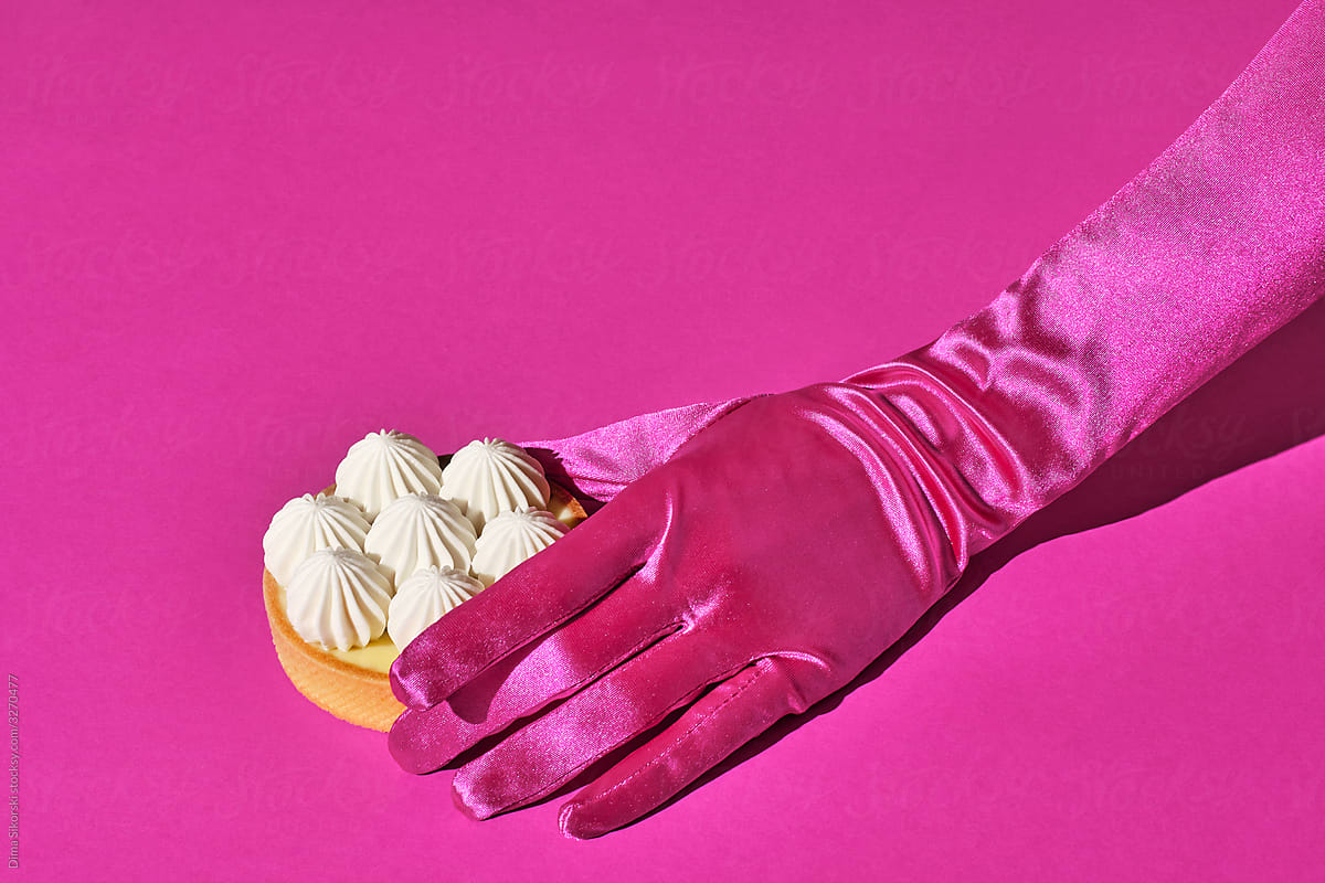 Luxurious dessert in a female hand on a pink background