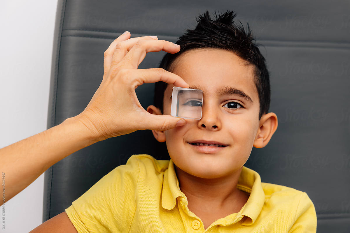 Anonymous person putting lens on eye of smiling kid