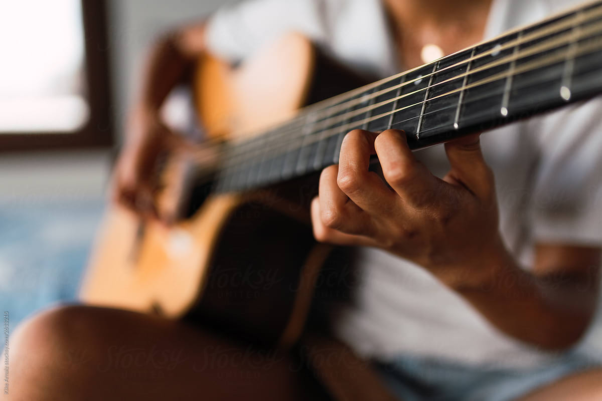 close up of woman hands playing guitar at home