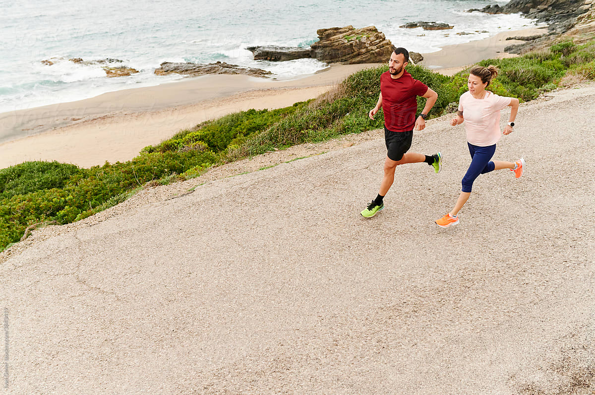 Fit couple running on a coastal road