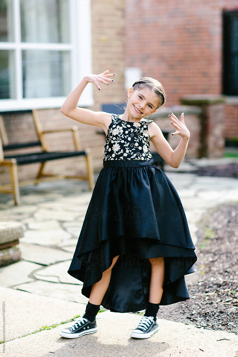 Young tween girl poses for photo in formal dress and sneakers