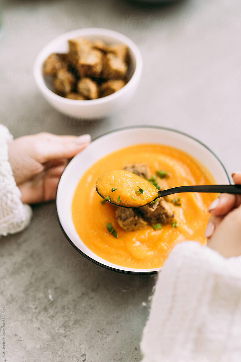 Person eats carrot sweet potato soup with homemade croutons