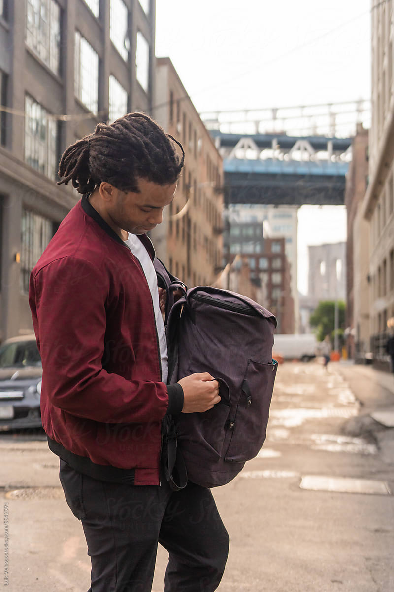 Black Man Checking His Backpack In The Street.