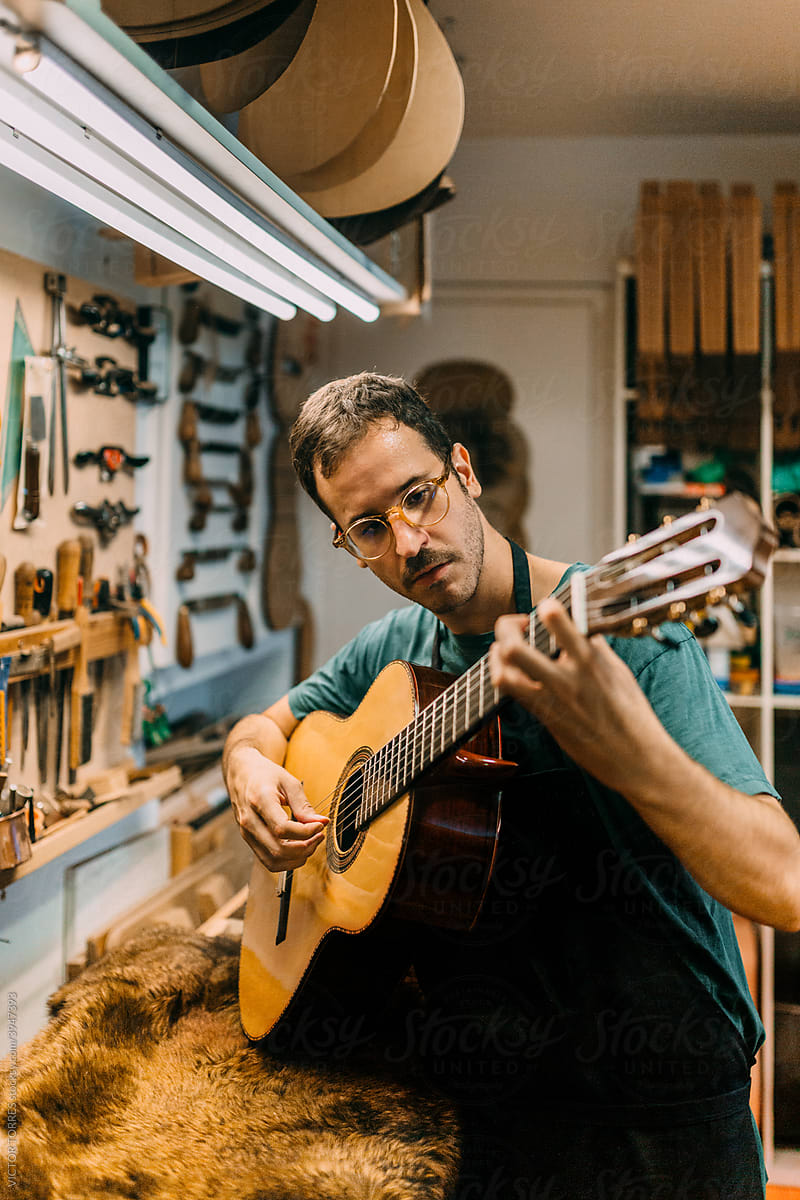 Luthier playing a spanish guitar to check the tuning and sound