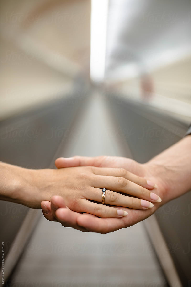 a woman\'s hand with an engagement ring on a man\'s hand