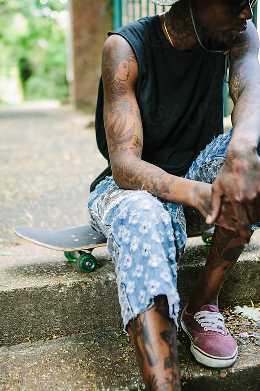 Portrait of a tattooed man with a skateboard