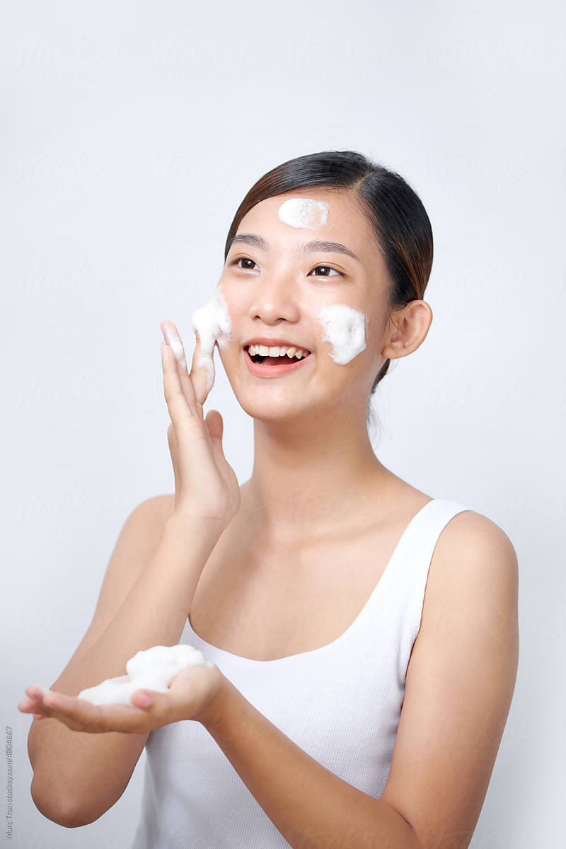 Smiling young woman washing foam face by natural foamy gel.
