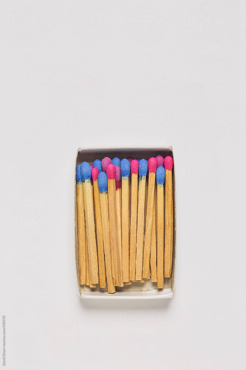 Red and blue wooden matches in a match box on white