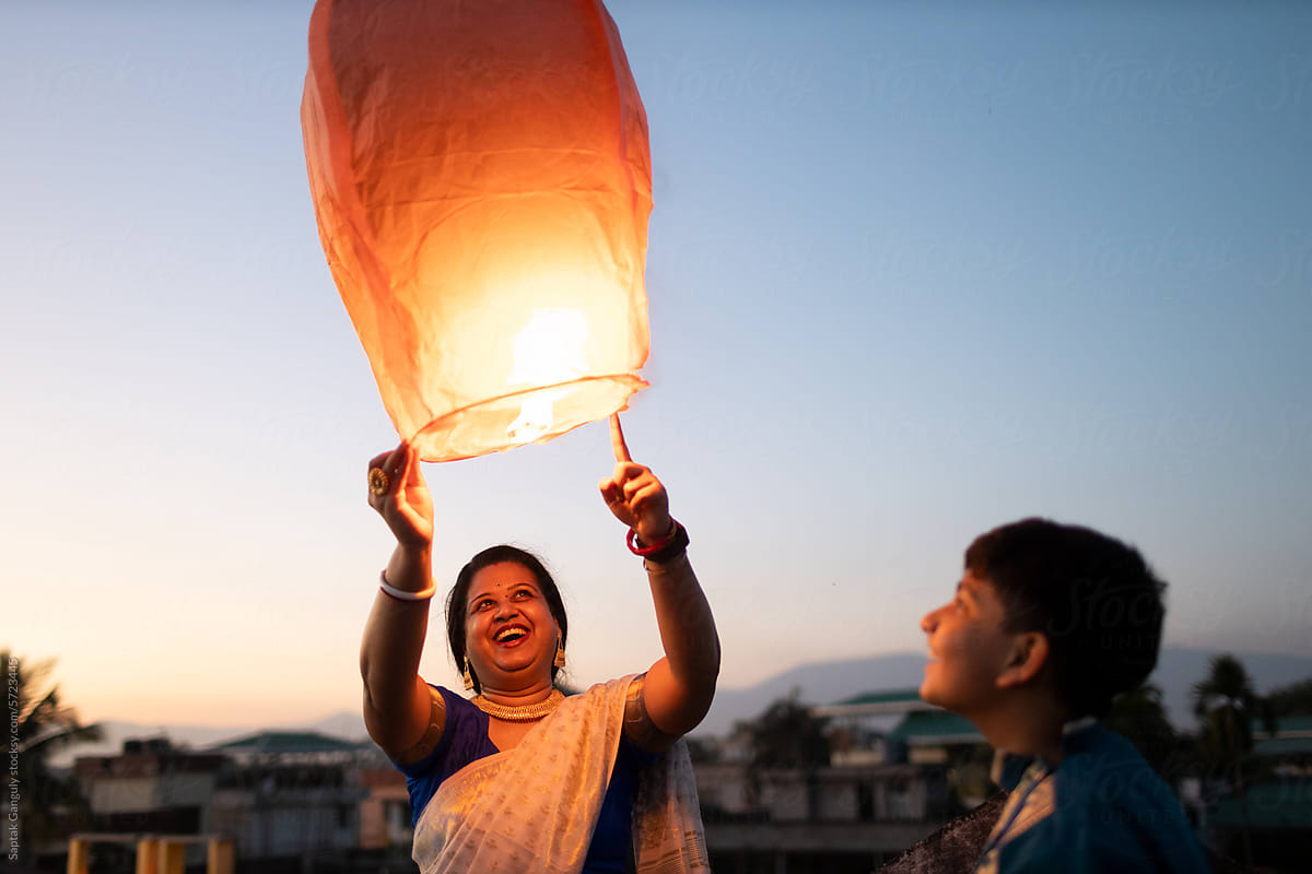 Mother and son releasing sky lantern at twilight