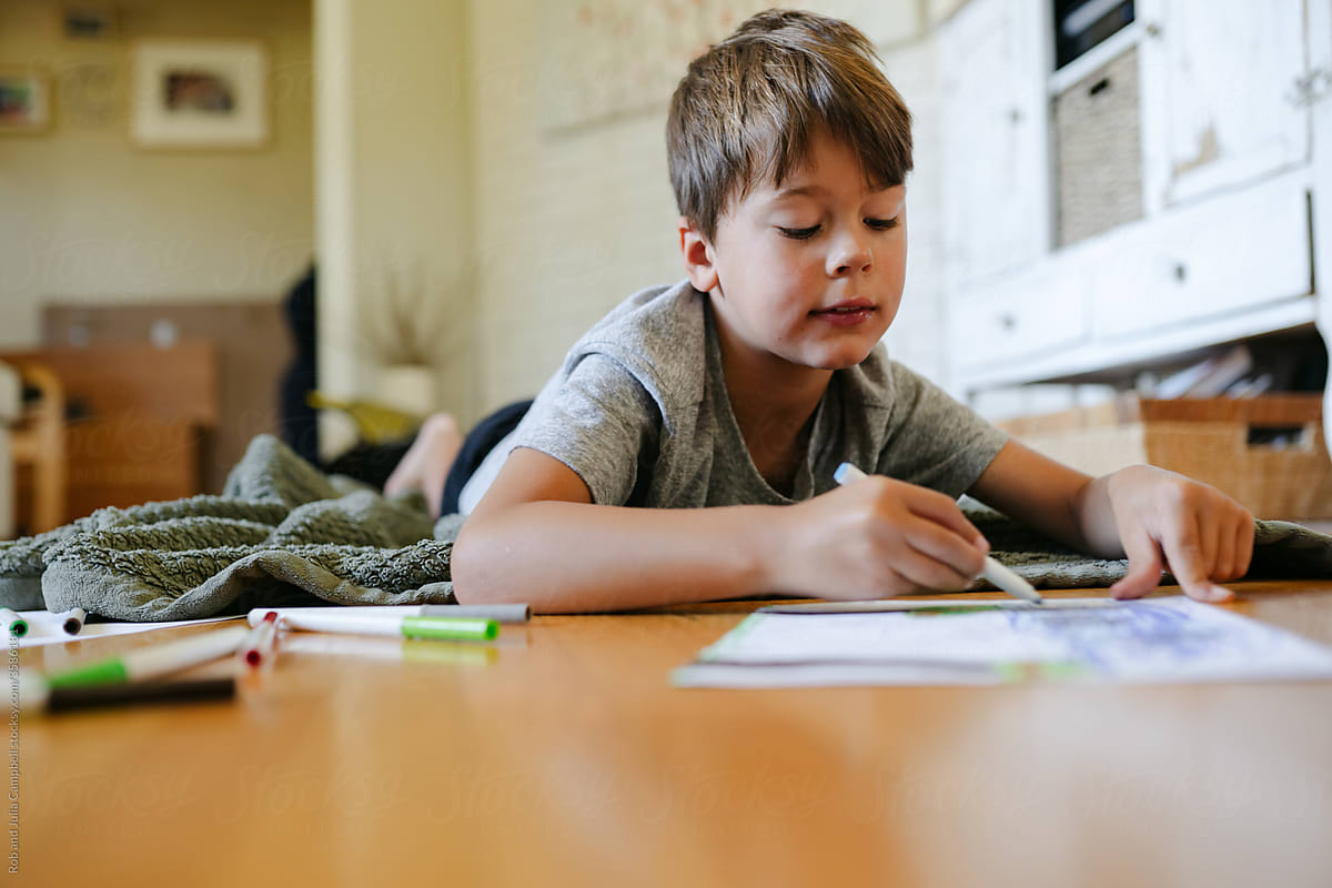 Young boy coloring on the floor.