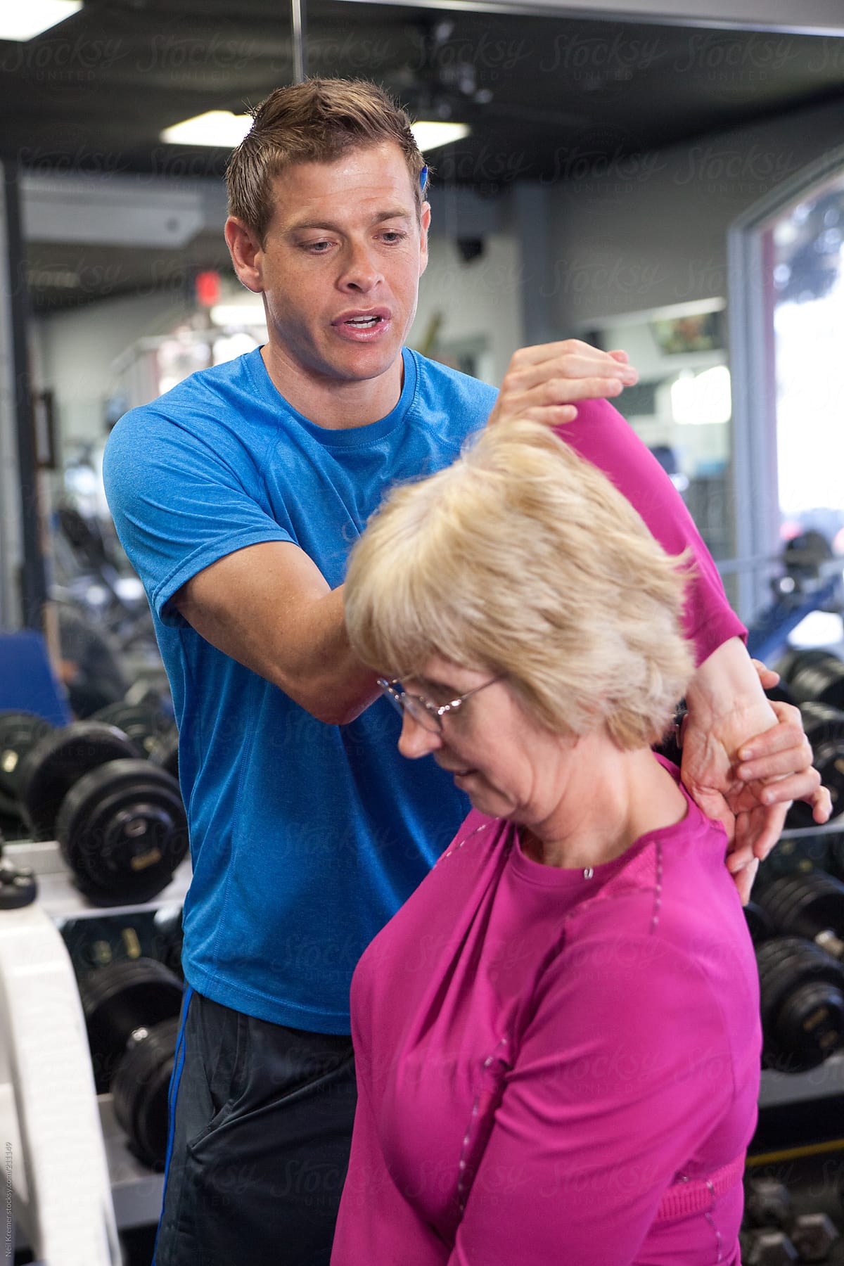 Male personal trainer helping senior woman rehab