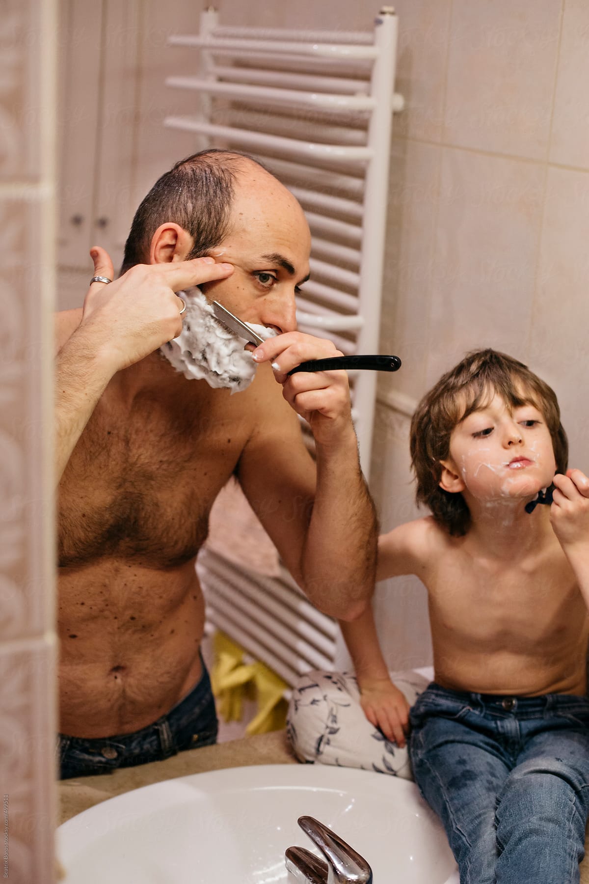 Father and 6 years old son carefully shaving their faces