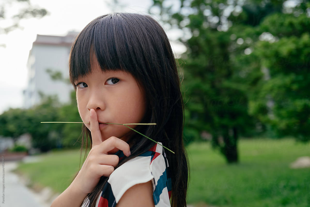 little girl biting a blade of grass