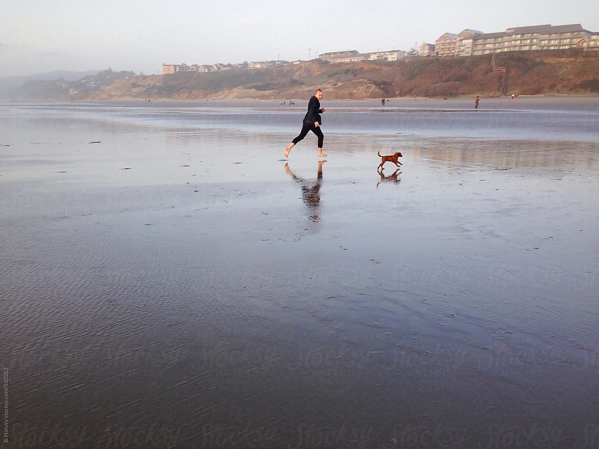 Man Running on Beach with Dog