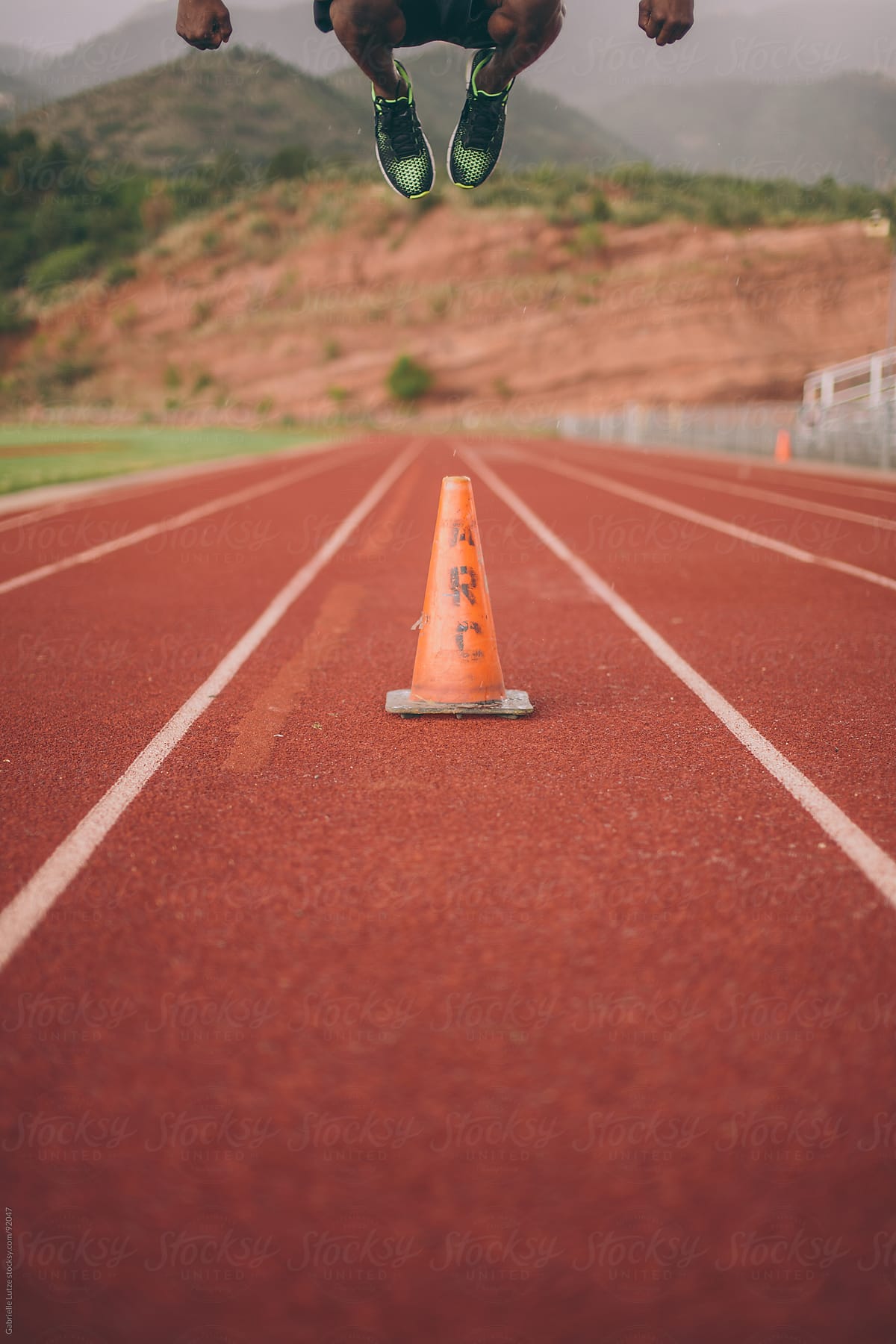 Black guy jumping over an orange cone on a track