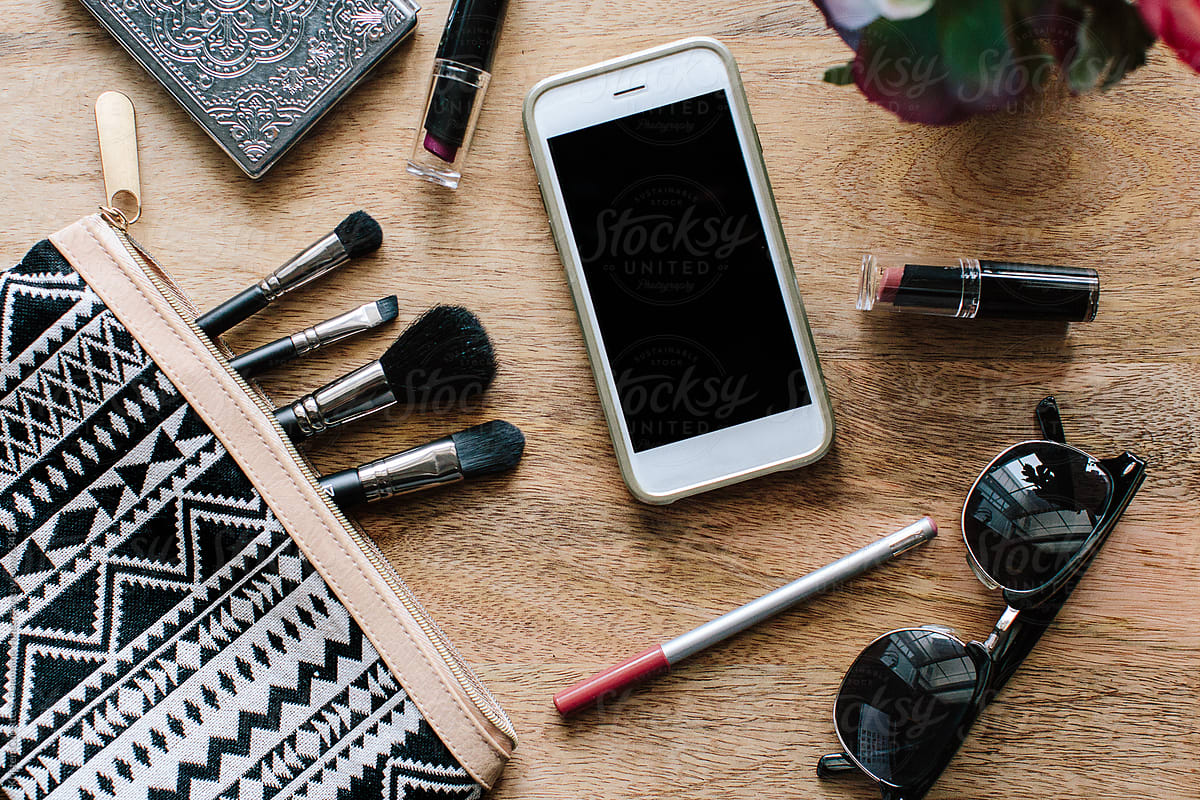 A cell phone with makeup and beauty essentials