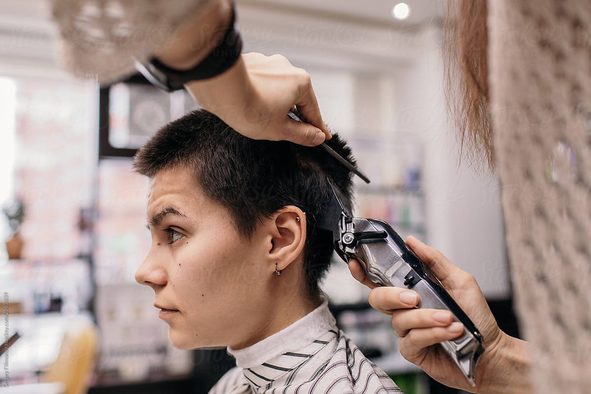 Hairdresser trimming hair of androgynous client
