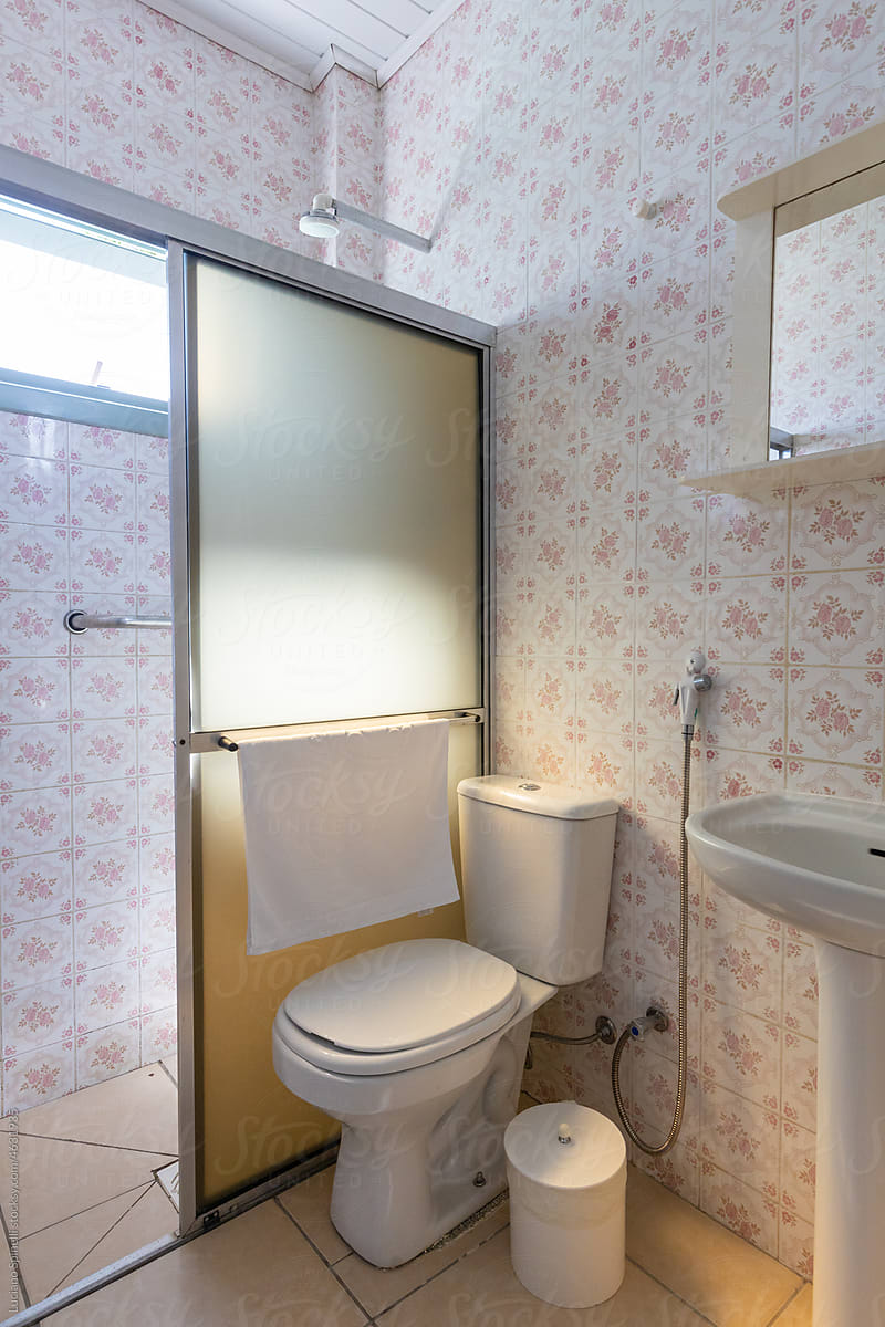 Vintage hotel bathroom with floral print tiles flooded with sunlight