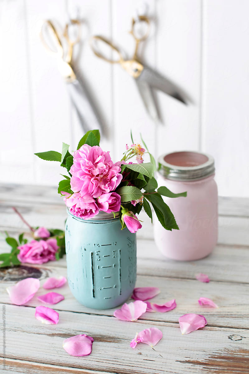 Mason jar with pink roses on table with scissors