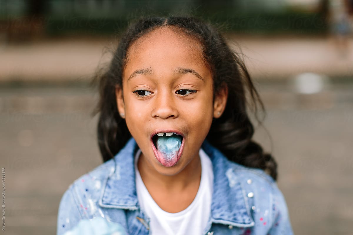 A little girl enjoying a popsicle & sticking her blue tongue out