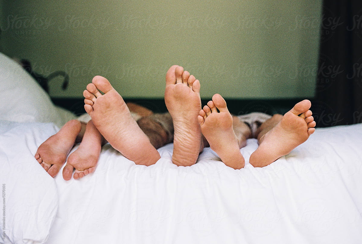 Adult and kids\' feet on a bed