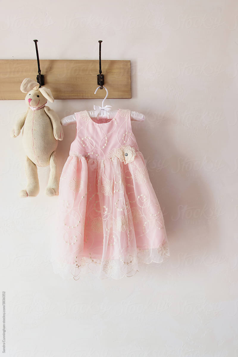 Little pink dress with a toy rabbit hanging on hooks