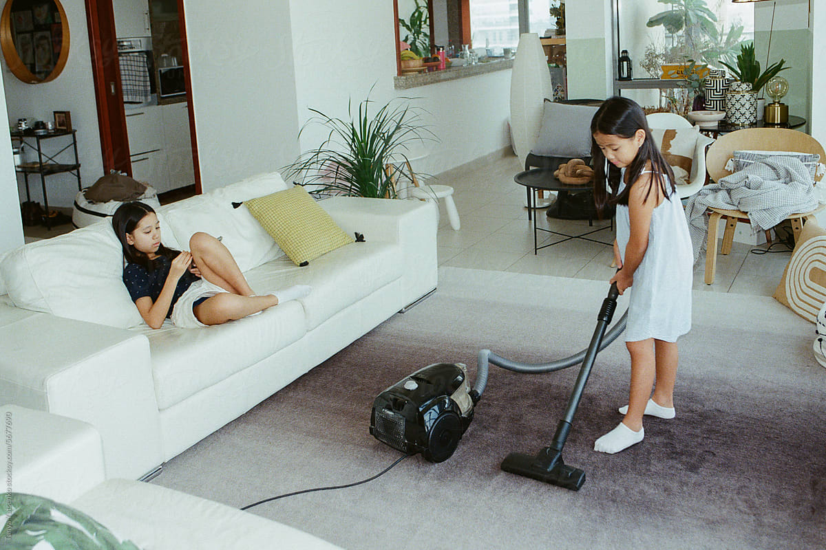 Girls at home. A girl vacuum-cleaning the carpet at home