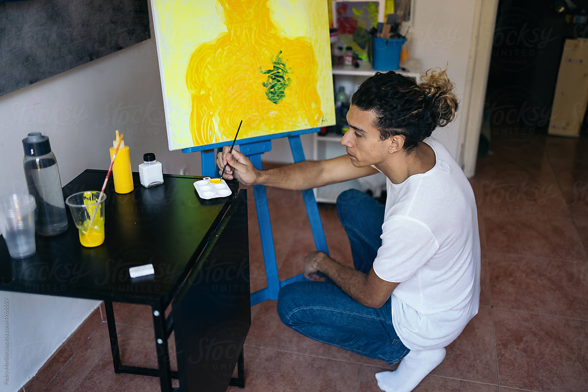 Young artist painting some details of his abstract work