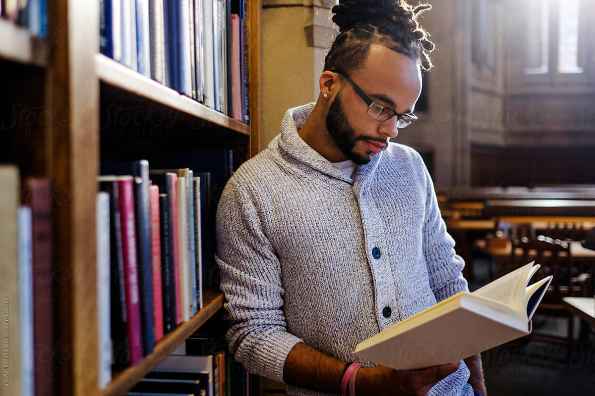 Male African American college student reading and studying in the library