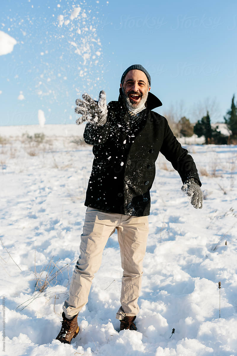 Happy bearded Man throwing snow to camera smiling