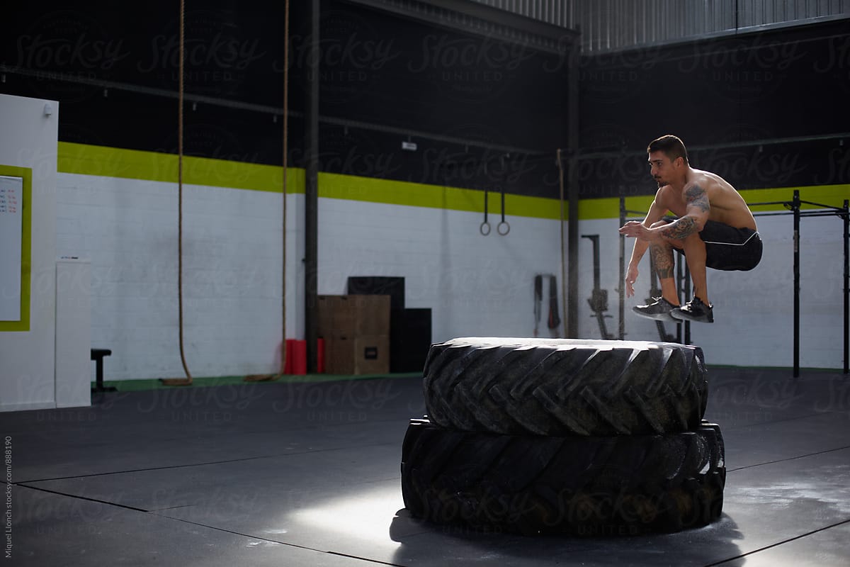 Fit man jumping over two big tires