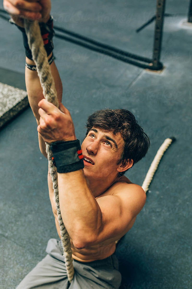 Young Man Climbing Rope And Looking Up by Stocksy Contributor VICTOR  TORRES - Stocksy