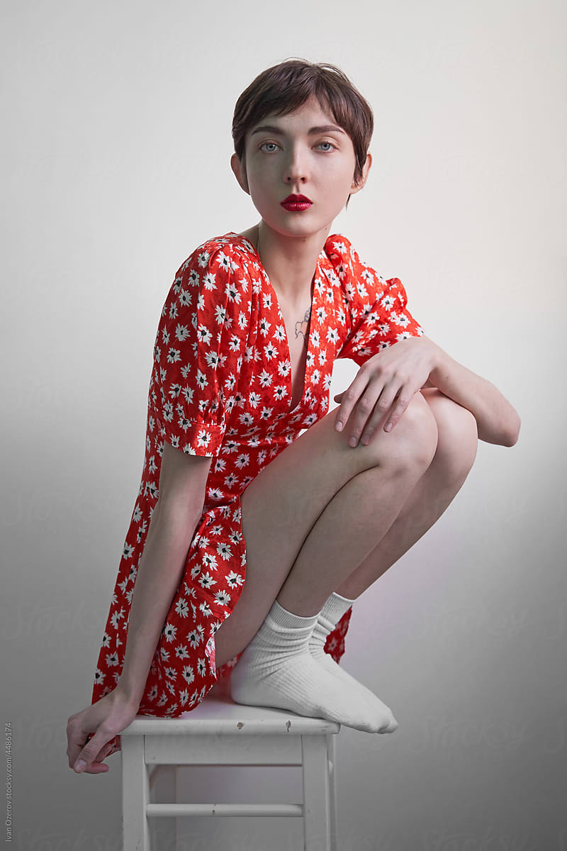 Woman in red floral dress sitting on stool