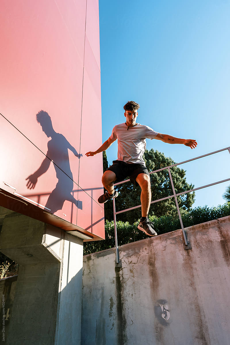 Young man jumping from fence on street