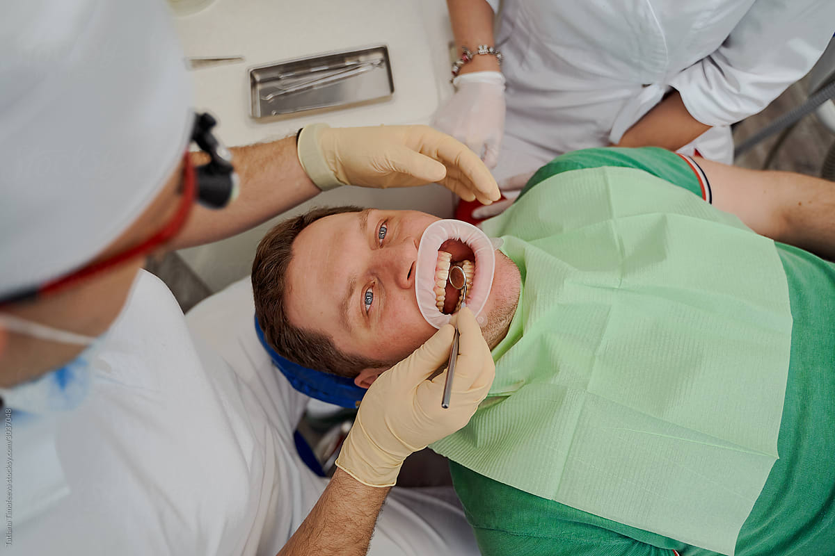 a man is lying in a dentist\'s chair with his mouth open