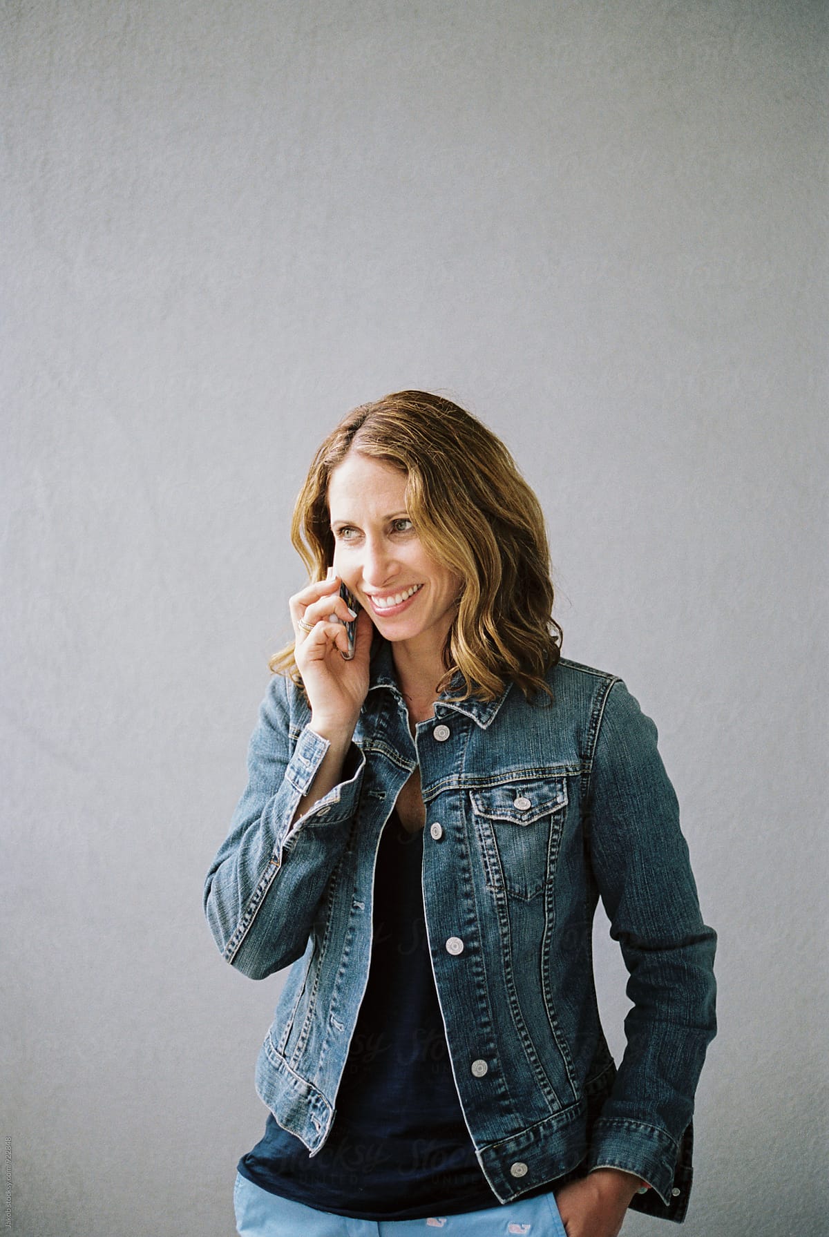 Attractive woman in a denim jacket smiling and talking on the phone