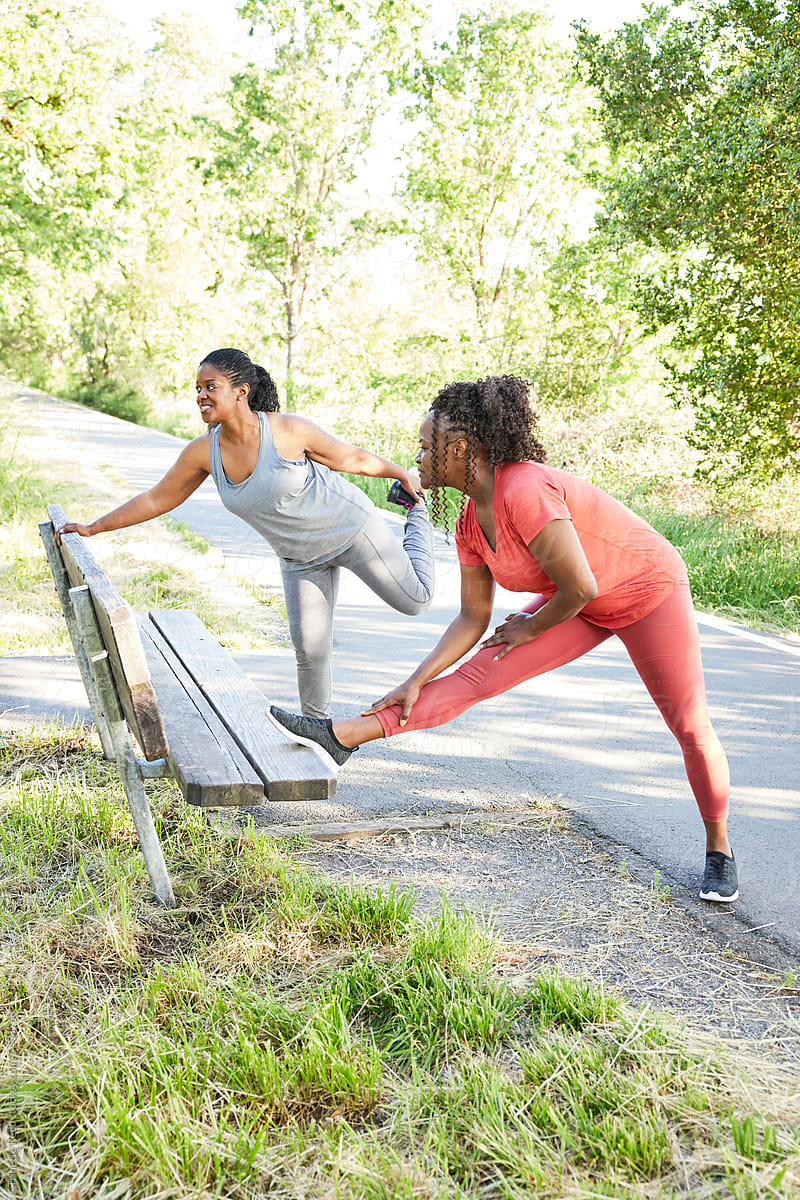 Mature Black women friends stretching together before exercising