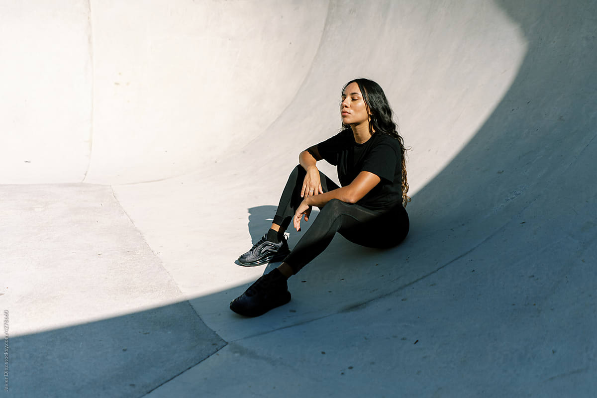 Sportswoman sitting on skate ramp