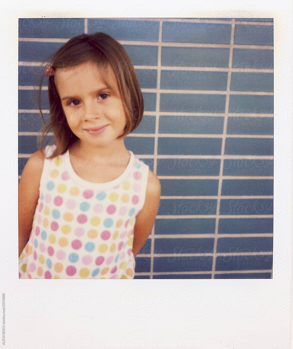 Vintage Polaroid Portrait Of A Cute Girl Standing Against A Blue Wall Del Colaborador De