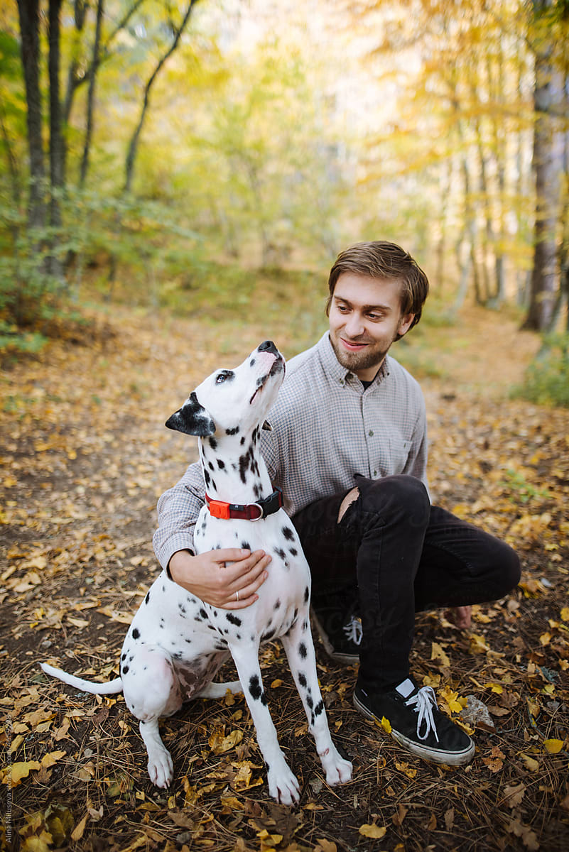 Smiling man with Dalmatian dog in autumn forest