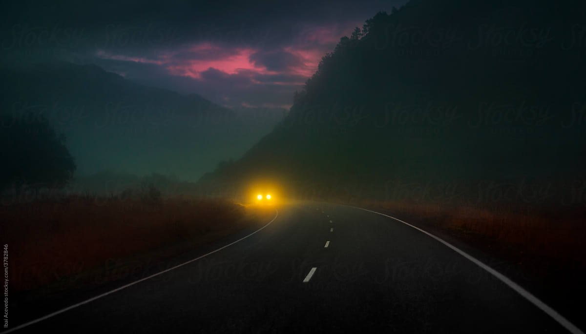 Car with yellow lights driving on a misty beautiful dark road