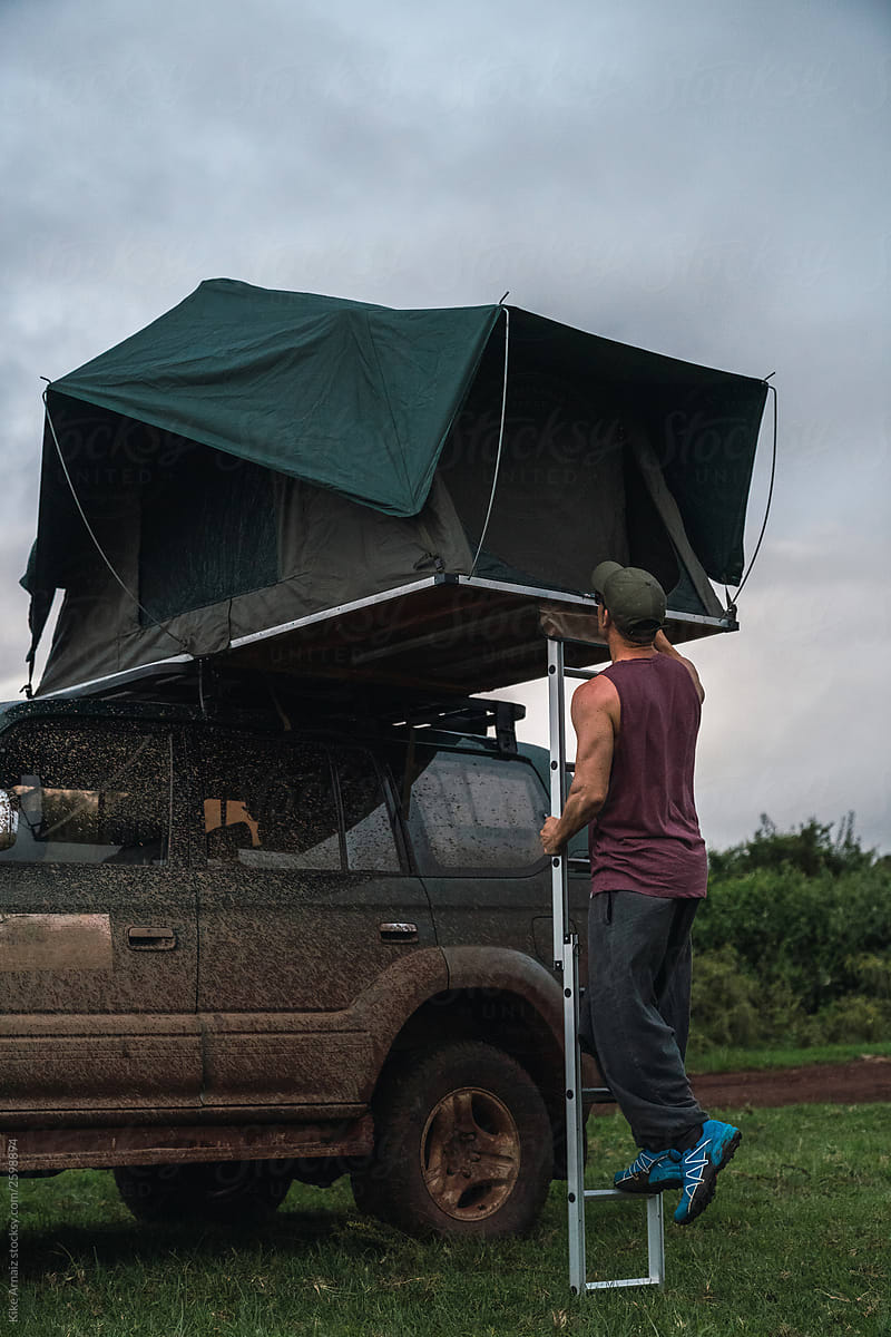 Man prepares the tent on a muddy vehicle. Ready to spend the nig