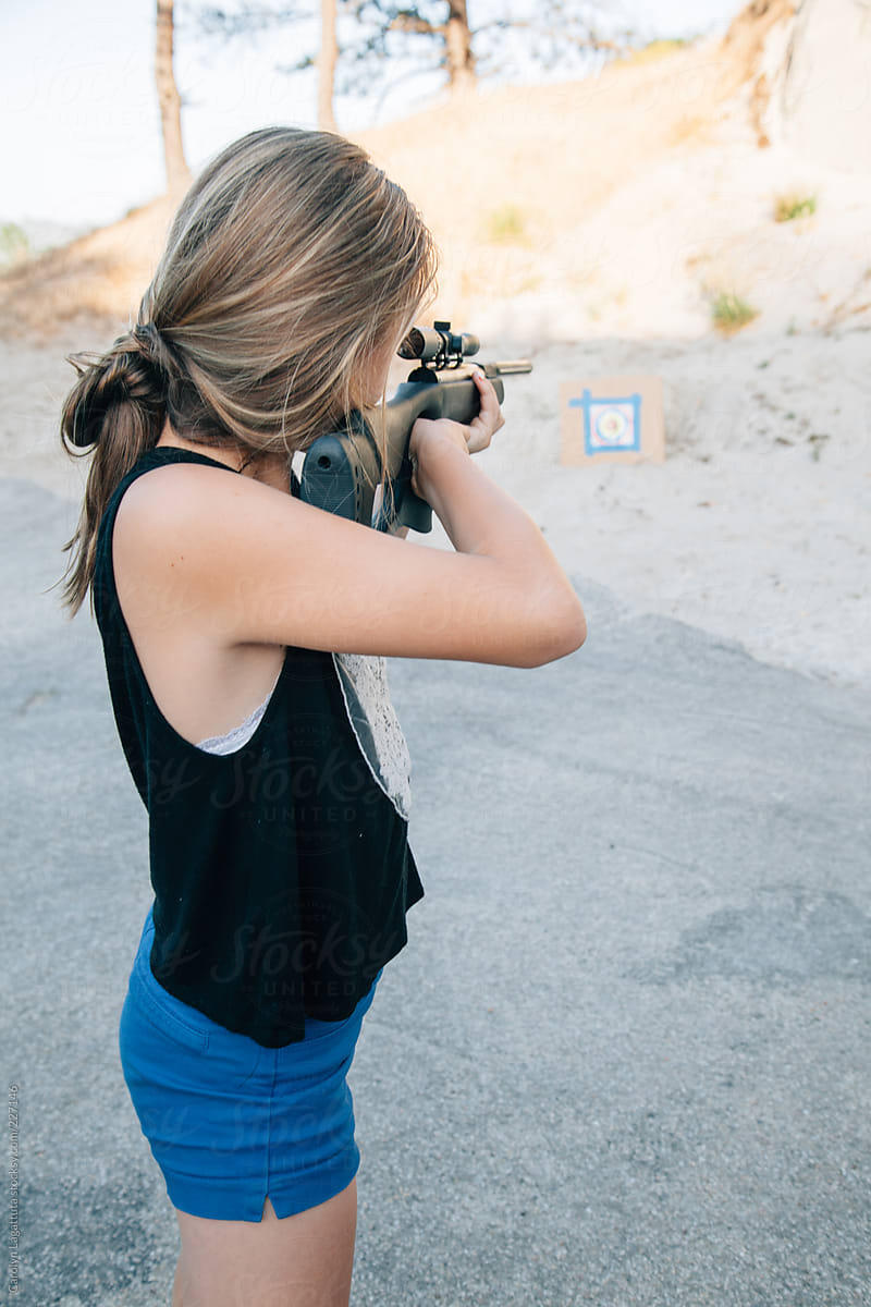 Teen Girl Shooting A Pellet Gun At A Target In The Sand