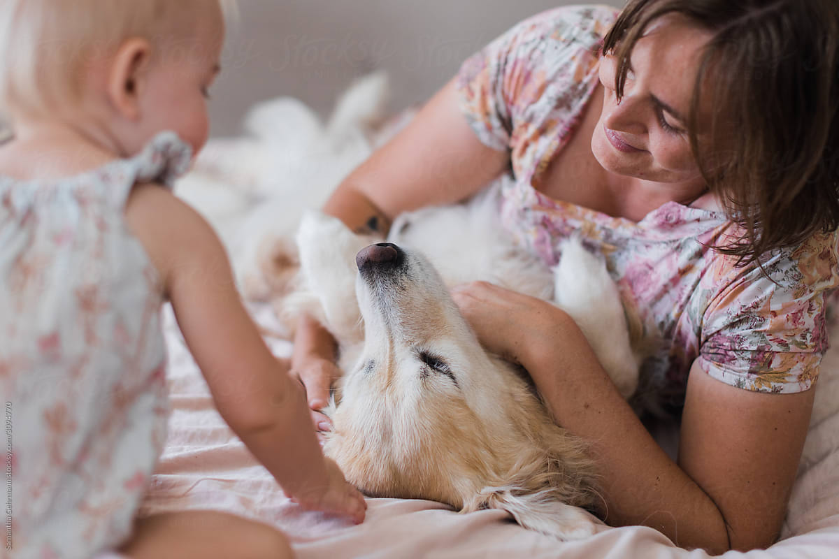 Mother and daughter patting golden retriever