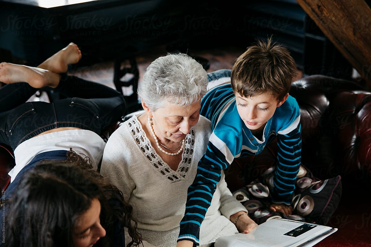 Boy showing an interesting fact in a book to his grandma and sister